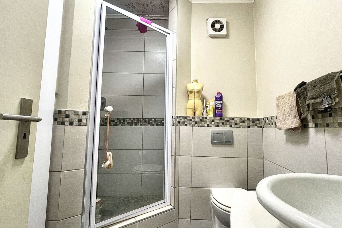 Compact bathroom featuring a corner shower enclosure, wall-mounted toilet, and basin with mosaic tile accents.