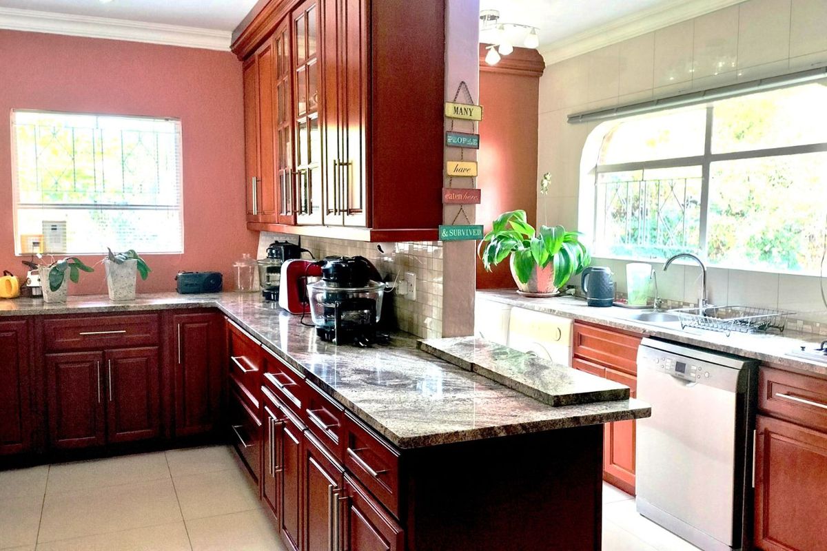 A spacious kitchen featuring dark wood cabinetry, granite countertops, and a functional layout with integrated sink and stove areas.