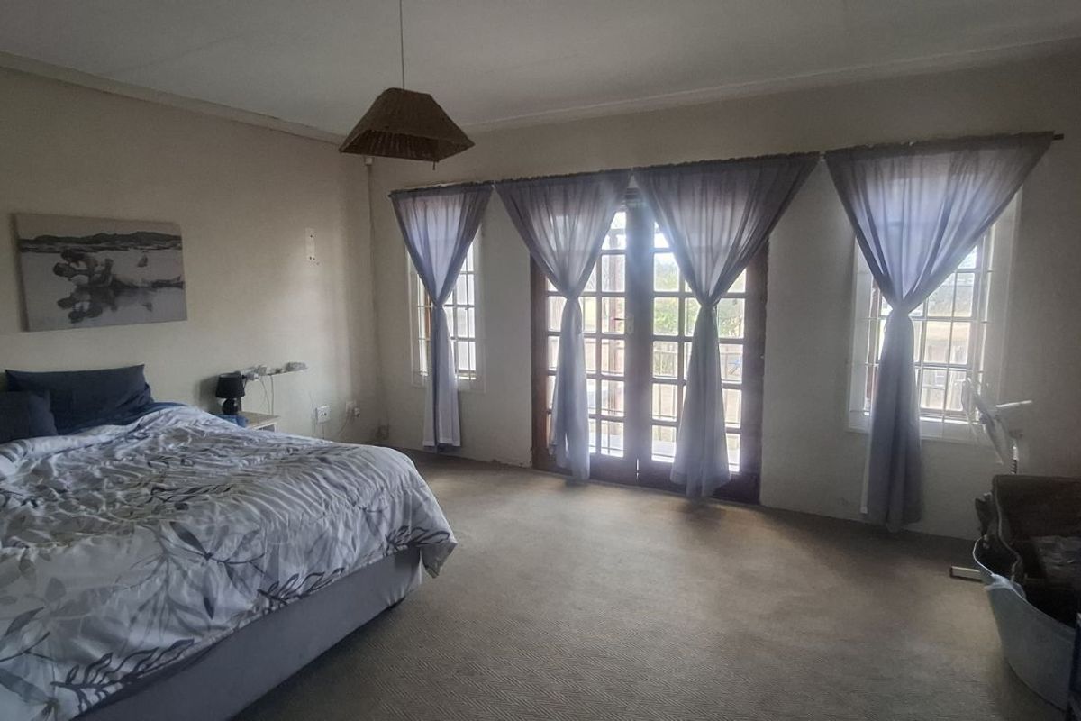Spacious bedroom featuring neutral walls, carpeted flooring, and double glass-paneled doors providing access to the exterior.