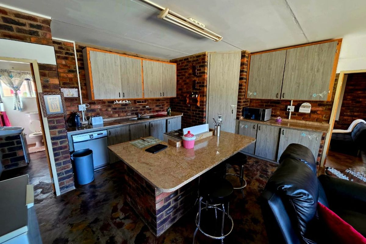 Rustic kitchen featuring exposed brick walls, granite-topped central island, built-in cabinetry, and integrated sink, offering a warm, character-filled farmhouse aesthetic.