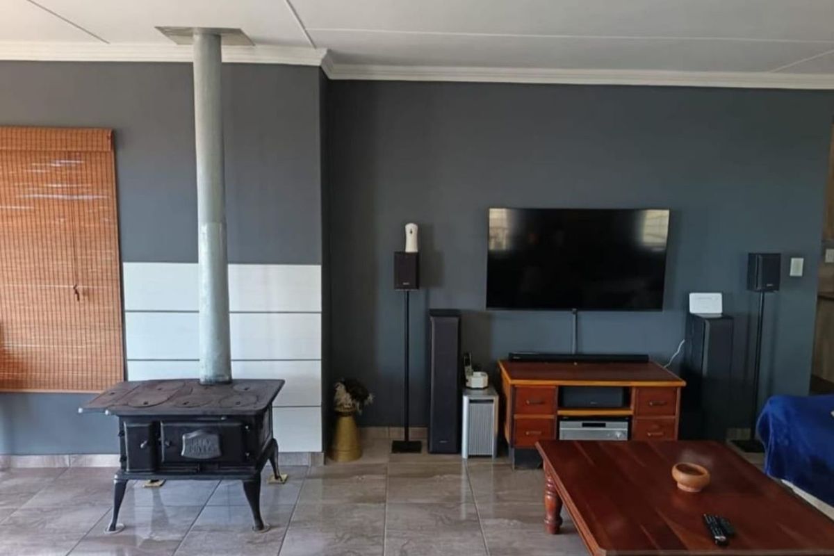 A living room featuring a cast iron wood-burning stove with a flue, tiled flooring, and a dark accent wall.