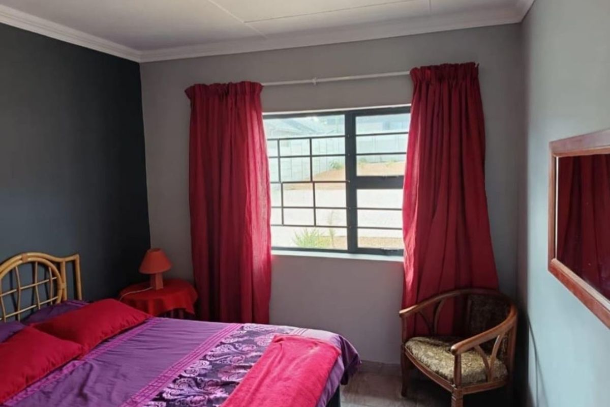 A bedroom featuring a window with security bars and neutral wall finishes.