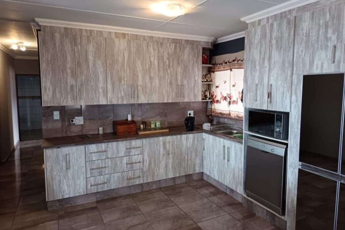 A functional kitchen featuring wood-look cabinetry, tiled backsplash, built-in oven, and integrated microwave space with tiled flooring.
