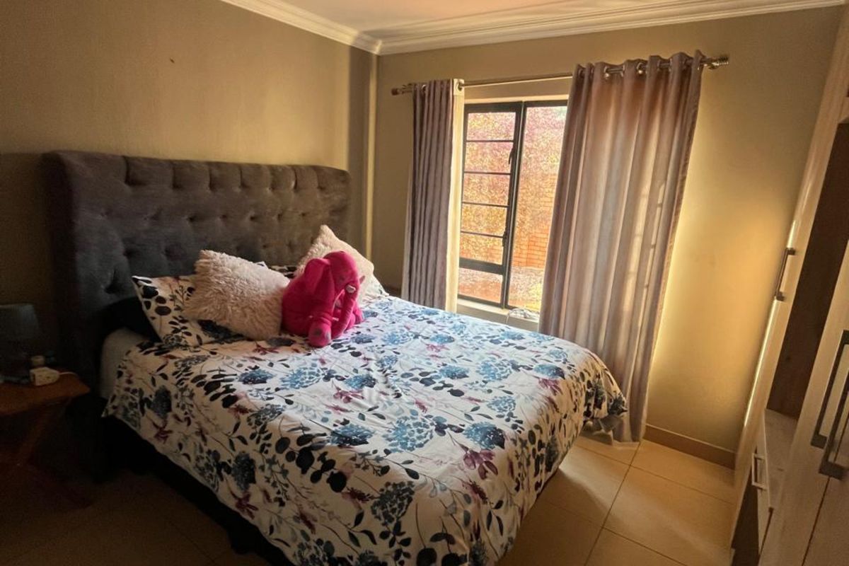 A bedroom featuring tiled flooring, crown molding, and a built-in wardrobe, providing a functional and comfortable living space.