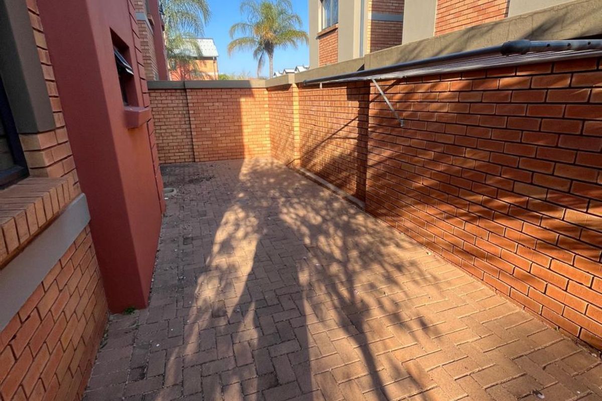 A private side courtyard featuring brick paving and high perimeter brick walls, providing a secure and low-maintenance outdoor space.