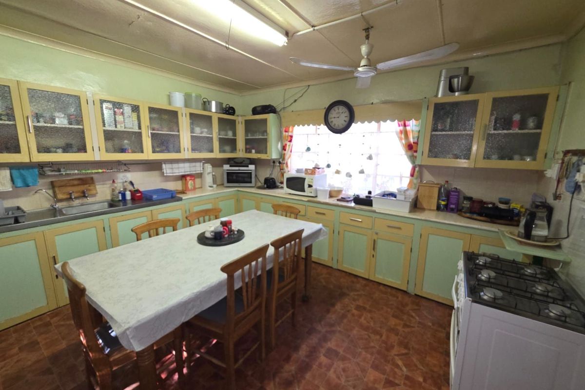 A dated kitchen featuring original cabinetry, a central dining area, and functional built-in storage, offering significant potential for a modern renovation.