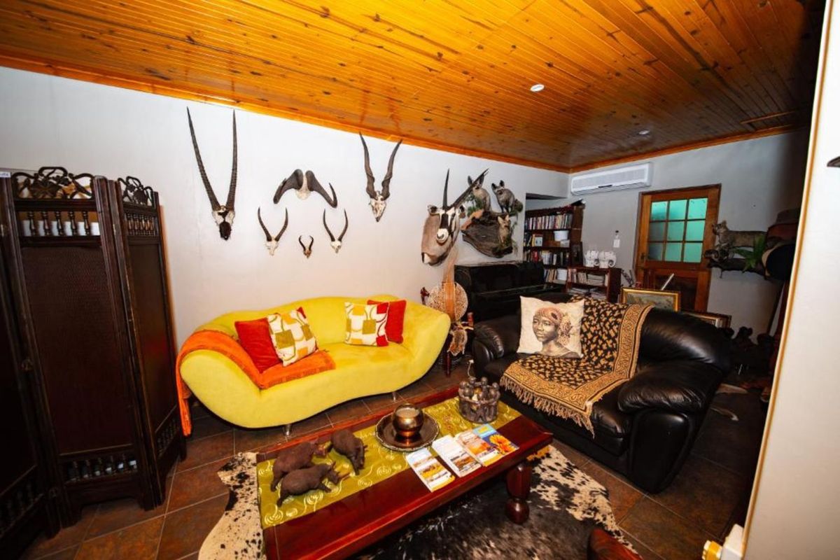 A cozy living room featuring a warm timber-clad ceiling, tiled flooring, and a wall-mounted air conditioning unit.