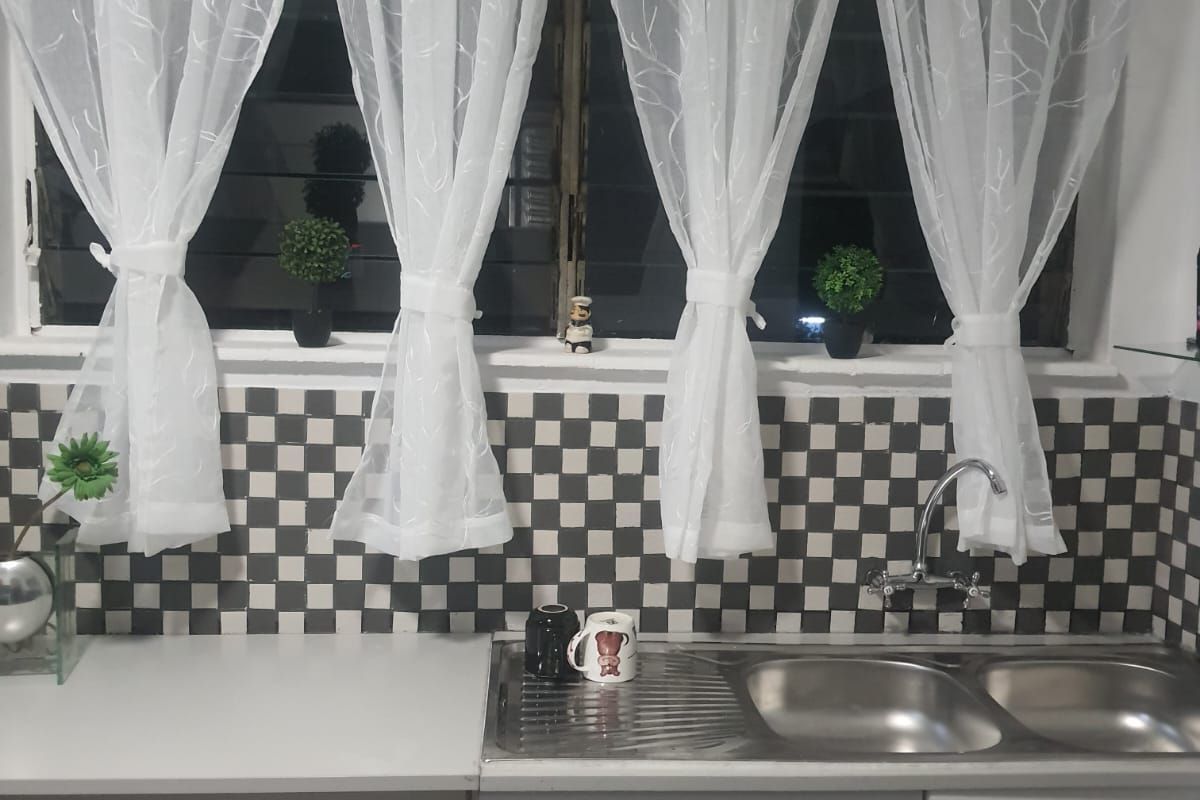 Kitchen sink area featuring a stainless steel double basin, chrome mixer tap, and a classic black and white checkered tile splashback.