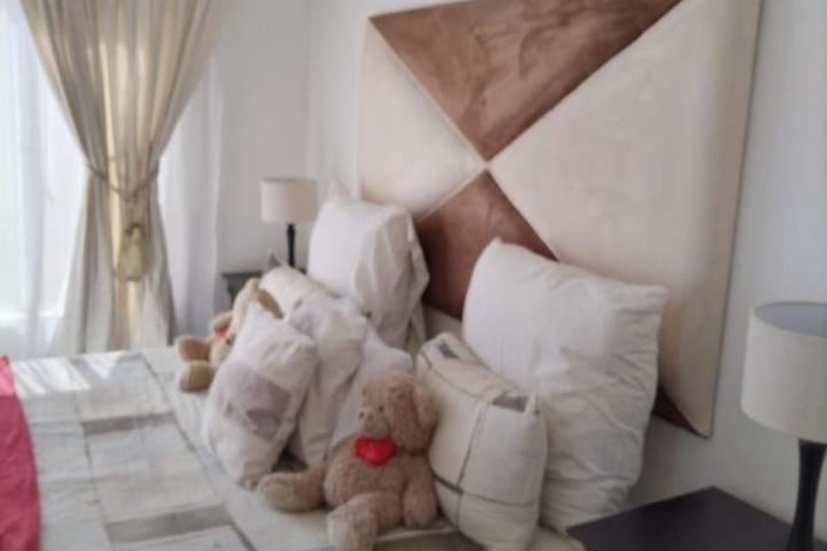 A bedroom featuring a geometric upholstered headboard and window with curtains.
