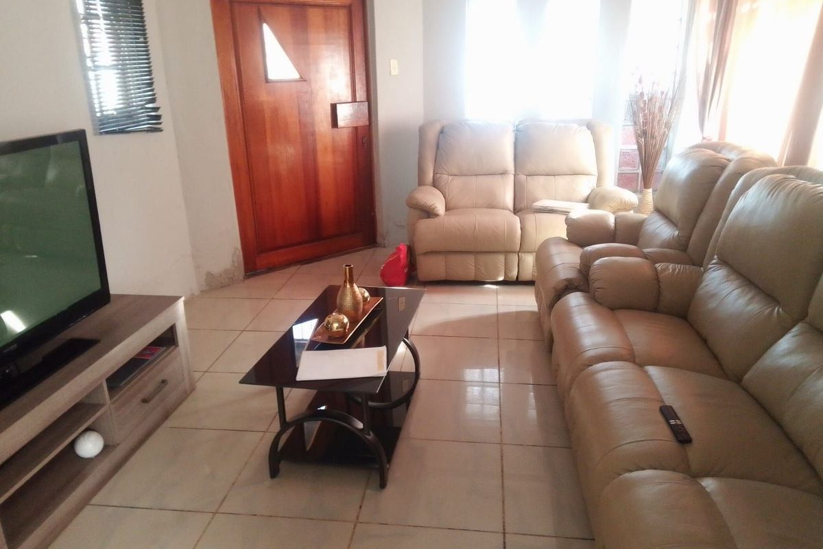 A living room featuring tiled flooring and a wooden entrance door, providing a functional and accessible living space.
