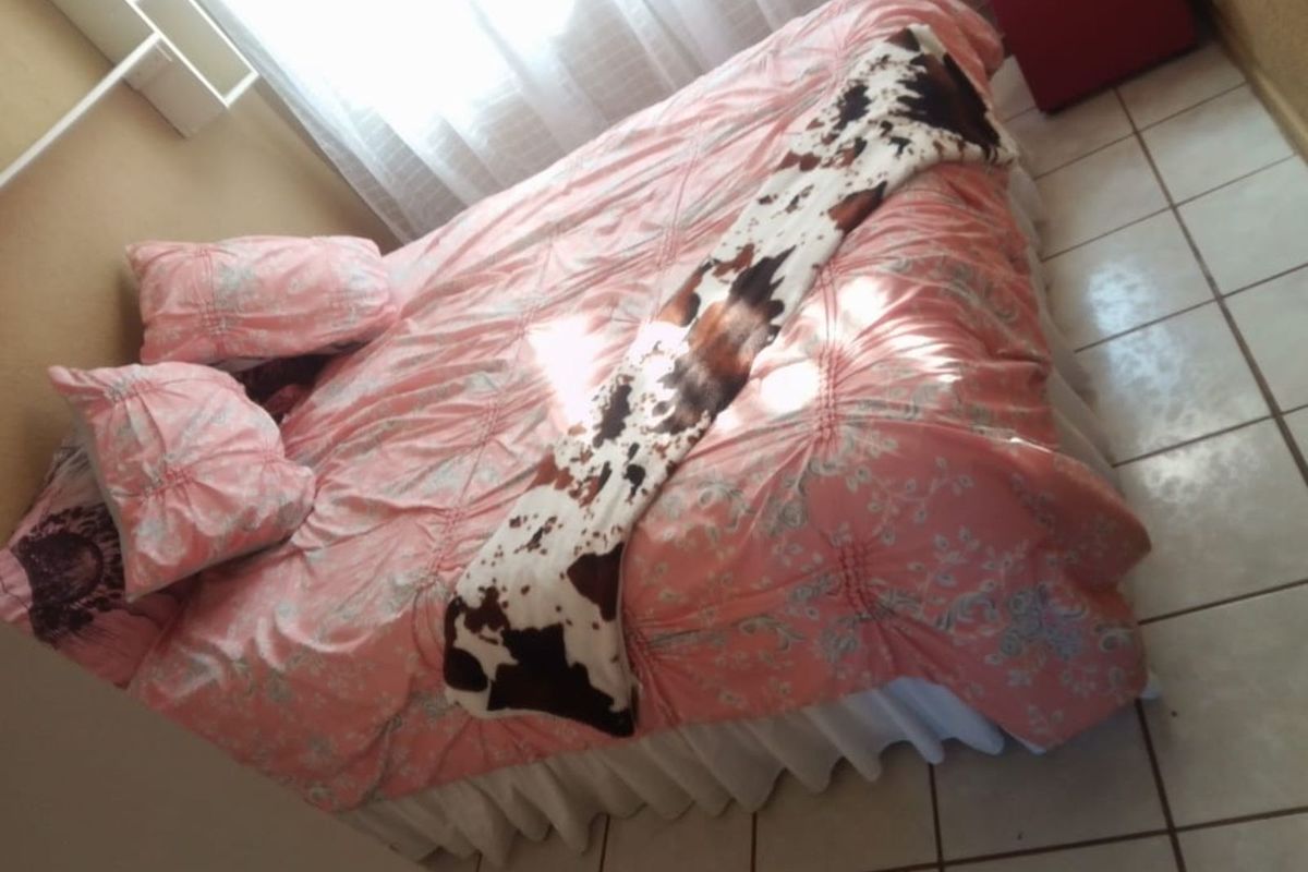 A bedroom featuring tiled flooring and a window with sheer curtains.