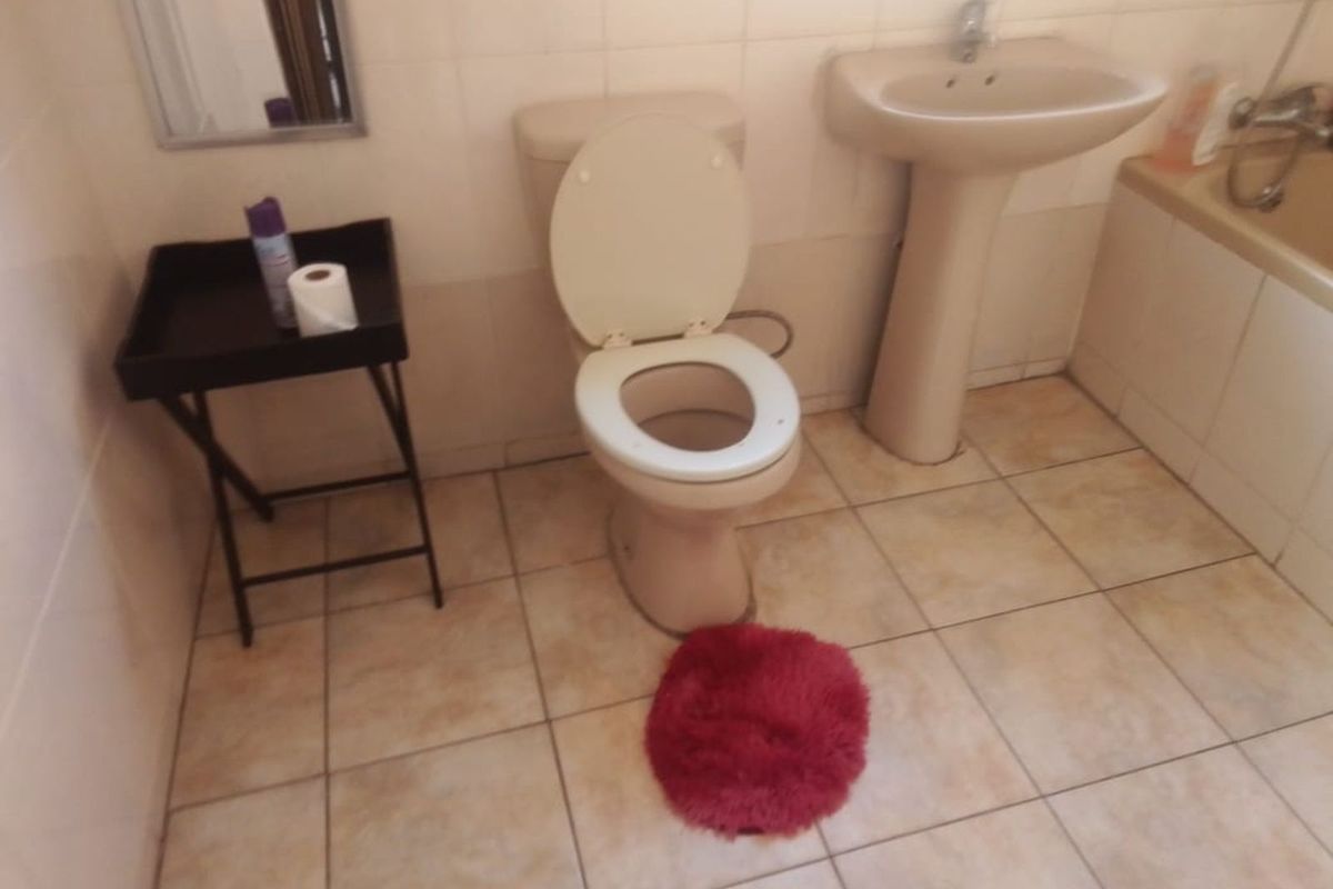 A dated bathroom featuring a pedestal basin, toilet, and bathtub with neutral wall and floor tiling.