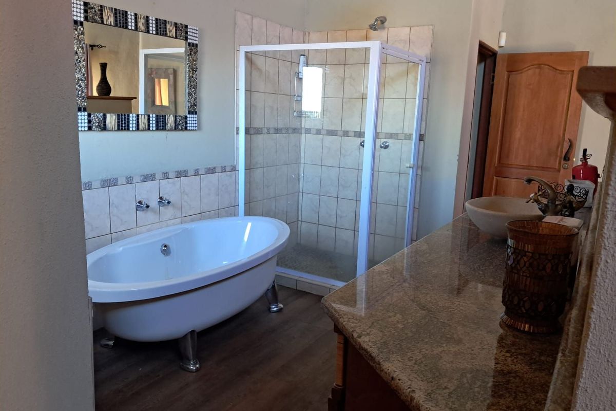 A well-appointed bathroom featuring a freestanding clawfoot bathtub, a separate glass-enclosed shower, and a granite-topped vanity with a vessel sink.