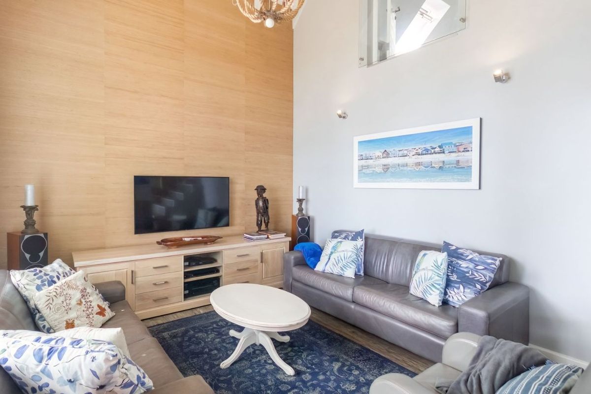 Spacious living room featuring high vaulted ceilings, a feature wood-paneled wall, and integrated wall-mounted lighting.