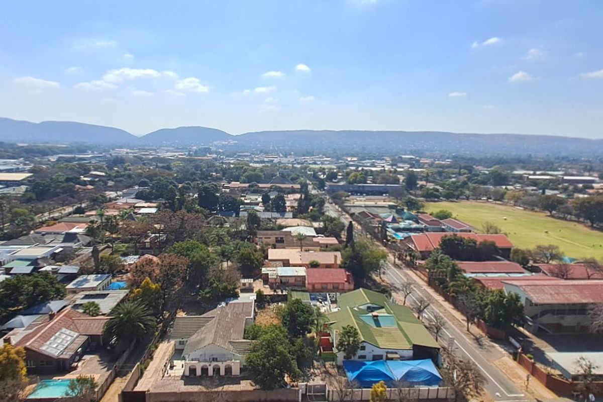 Elevated aerial view overlooking a suburban residential neighborhood with surrounding landscape and distant hills.