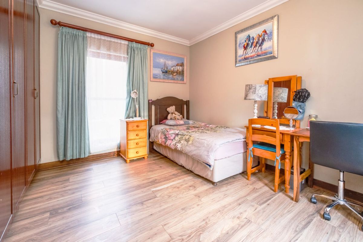 A bedroom featuring wood-look laminate flooring, built-in wardrobes, and a window with curtain rod.
