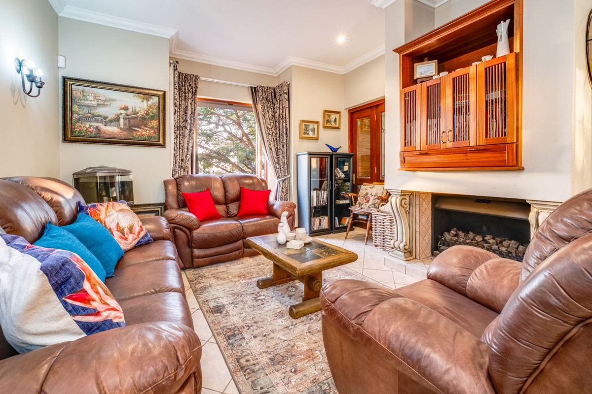 A cozy living room featuring a built-in fireplace with wooden cabinetry, tiled flooring, and large windows allowing natural light.