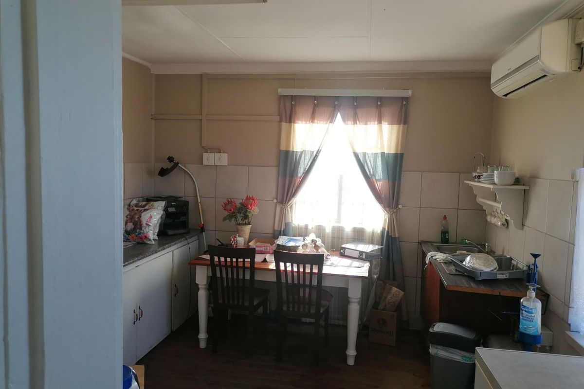 A compact kitchen area featuring built-in cabinetry, a stainless steel sink, and a wall-mounted air conditioning unit.