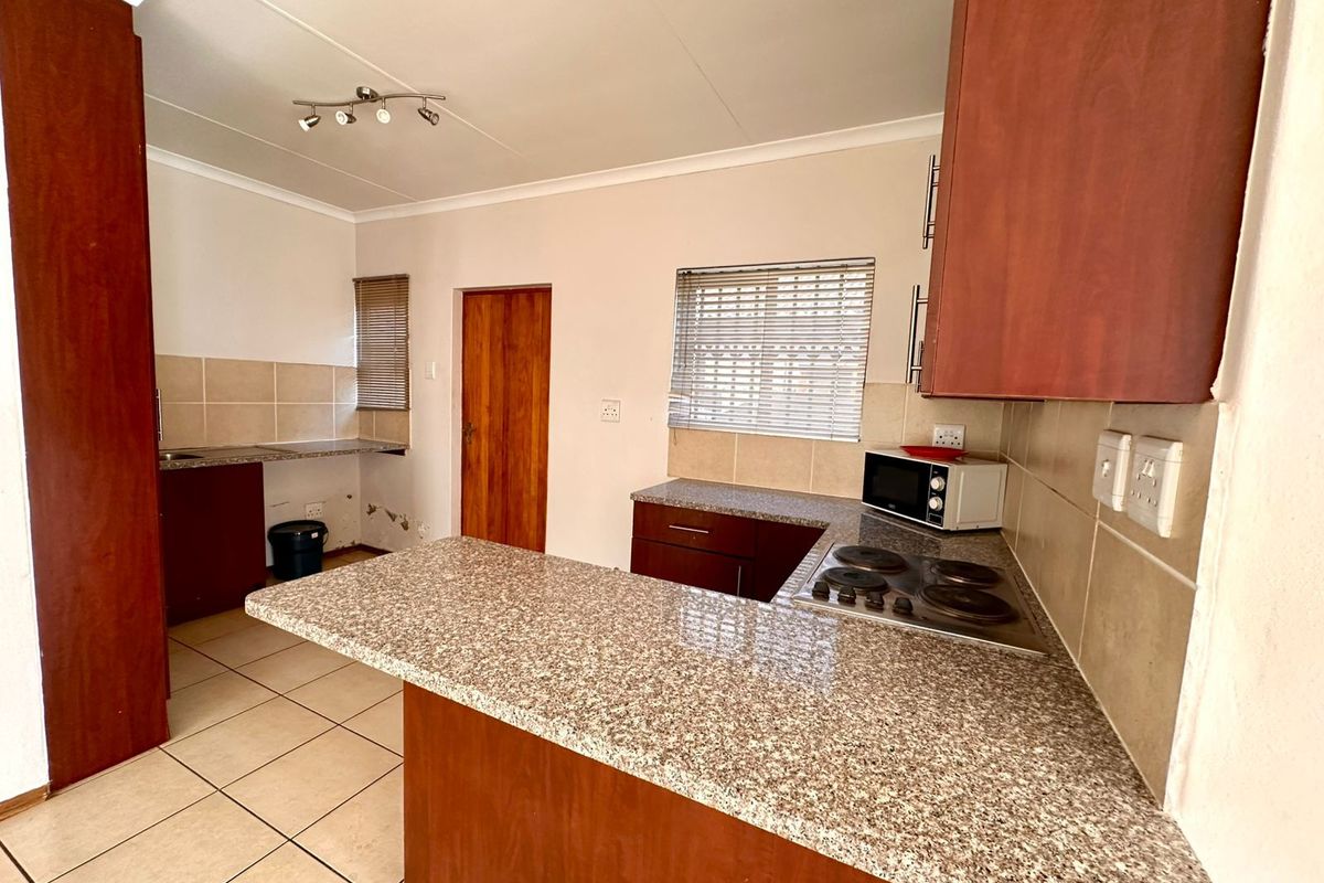 Functional kitchen featuring granite countertops, built-in hob, tiled flooring, and wooden cabinetry with a breakfast nook layout.