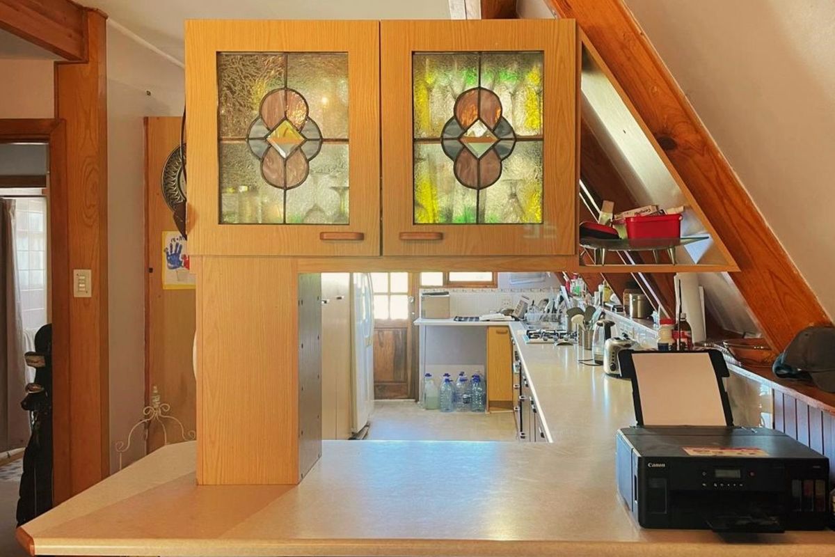 A kitchen featuring wooden cabinetry with decorative stained glass inserts, laminate countertops, and an angled ceiling design.
