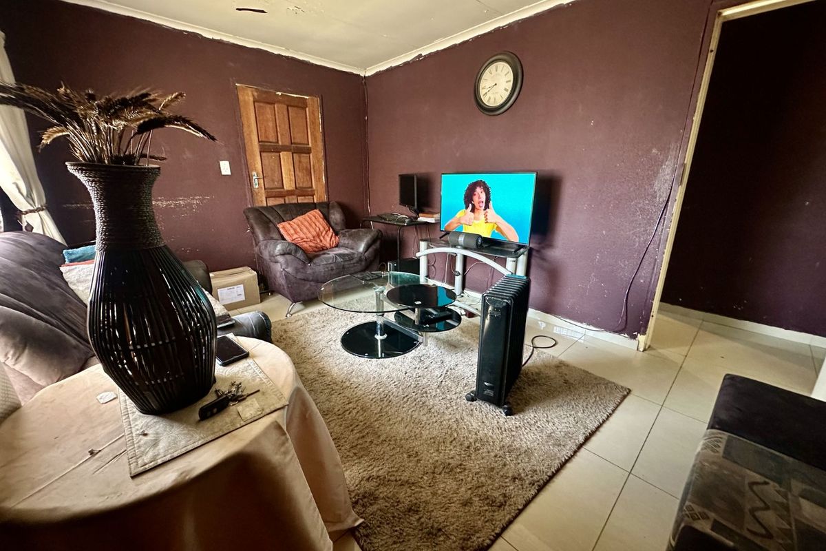 A living room featuring tiled flooring and dark-painted walls, requiring cosmetic updates to the ceiling and wall finishes to improve the overall aesthetic.