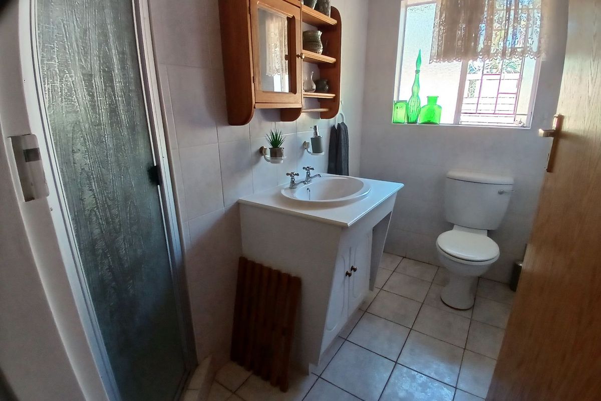 A functional bathroom featuring a shower enclosure, a vanity with a basin, and a toilet, finished with neutral wall and floor tiles.