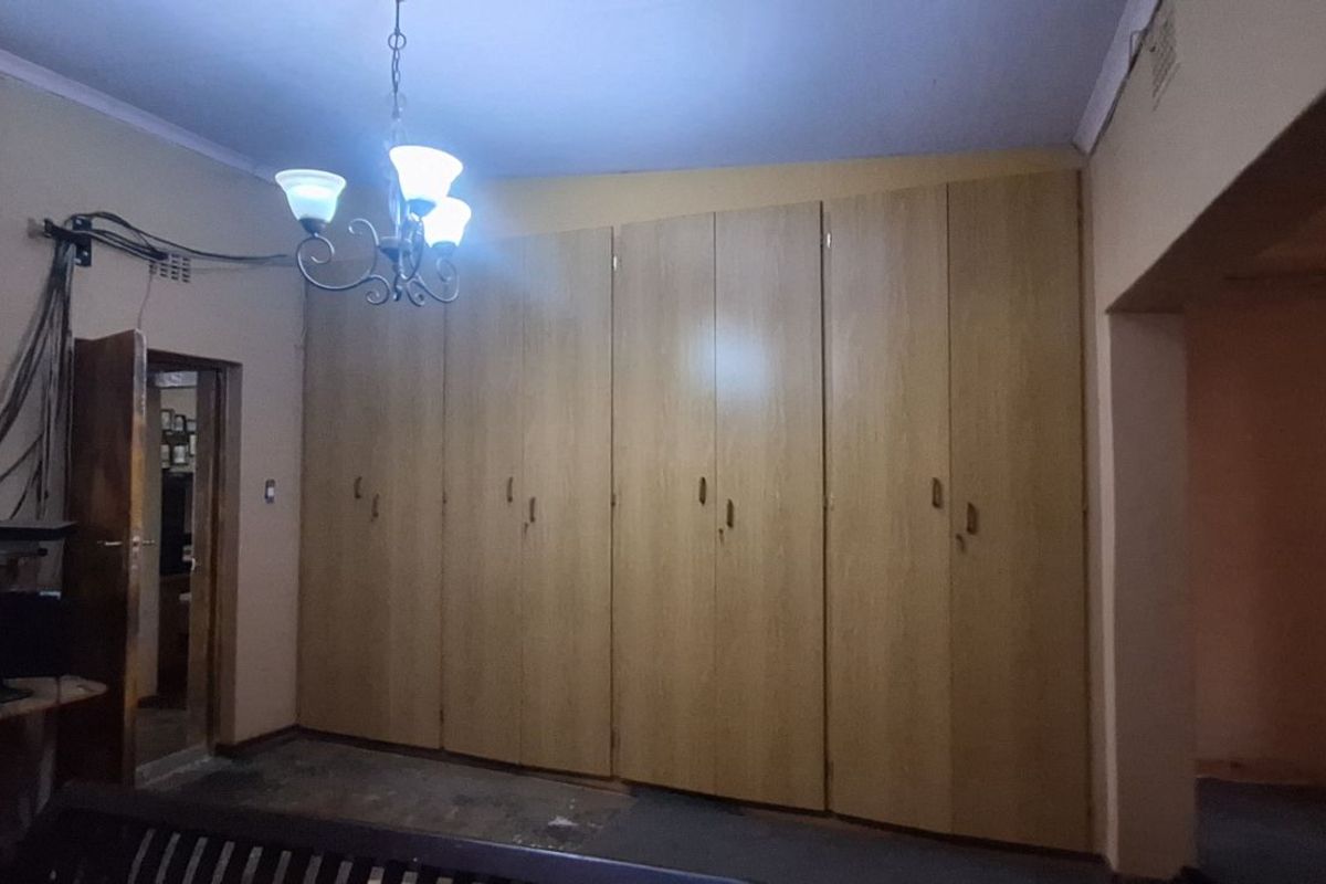 A bedroom featuring extensive built-in wooden cabinetry, providing ample storage space, with visible electrical wiring and a central light fixture.