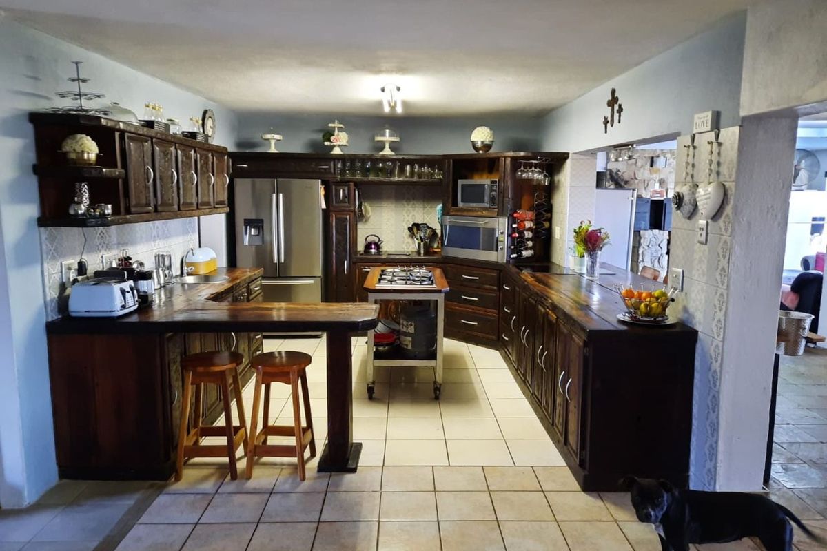 A spacious kitchen featuring dark wood cabinetry, a central mobile island with a gas hob, and tiled flooring, offering a functional layout.