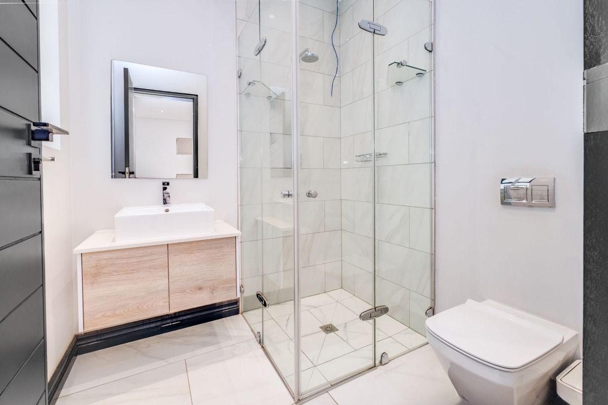 Modern bathroom featuring a glass-enclosed shower, wall-mounted toilet, and a contemporary vanity with a vessel sink.
