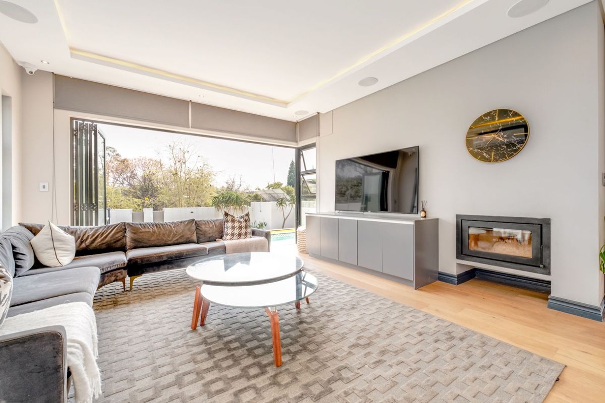 Modern living room featuring a built-in fireplace, recessed ceiling lighting, and large folding doors that open to an outdoor pool area.