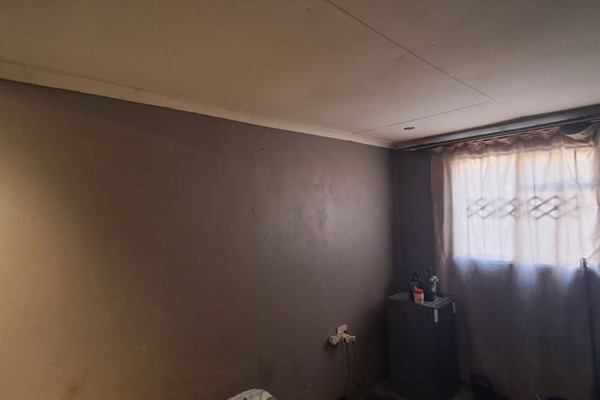 A bedroom featuring dark painted walls, a ceiling with visible seams, and a window with fitted curtain tracks.