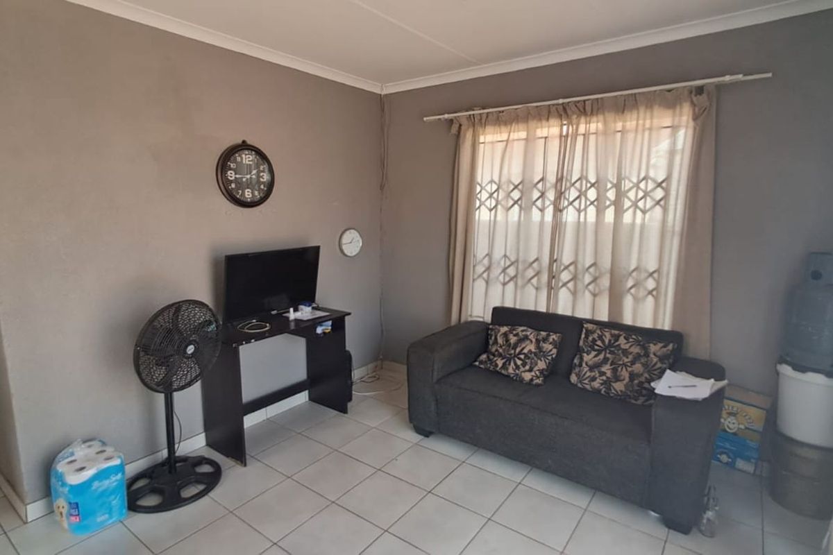 A living room area featuring tiled flooring and a security gate installed on the window.