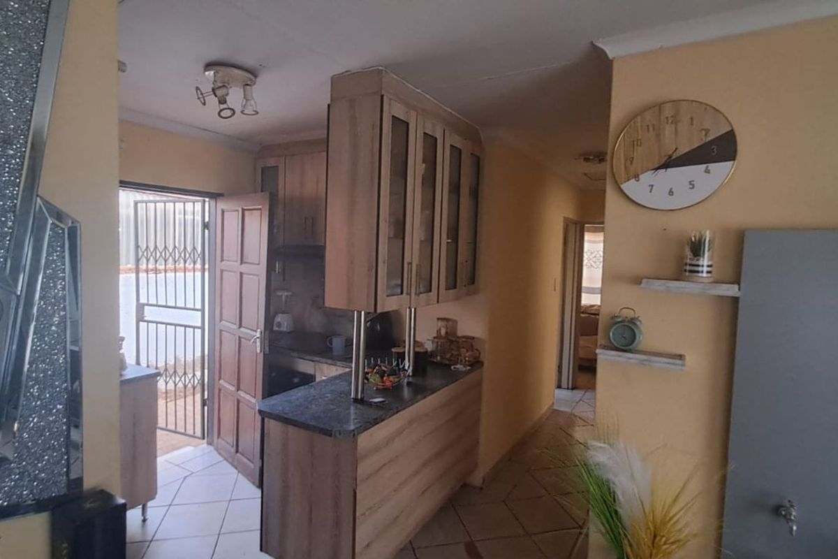 A functional kitchen area featuring wood-look cabinetry, a breakfast bar, and tiled flooring, with direct access to an exterior door.