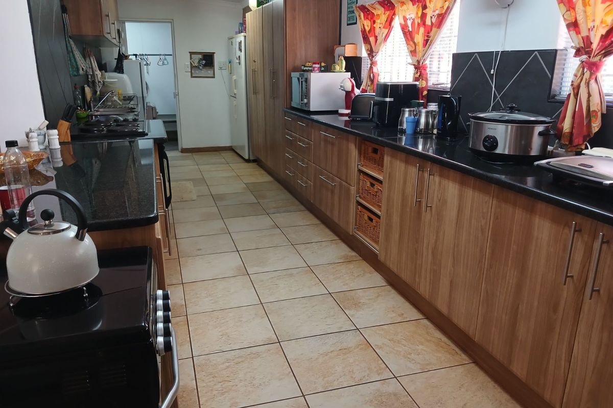 A functional kitchen featuring wood-finish cabinetry, dark granite countertops, tiled flooring, and a built-in stove with an integrated layout.