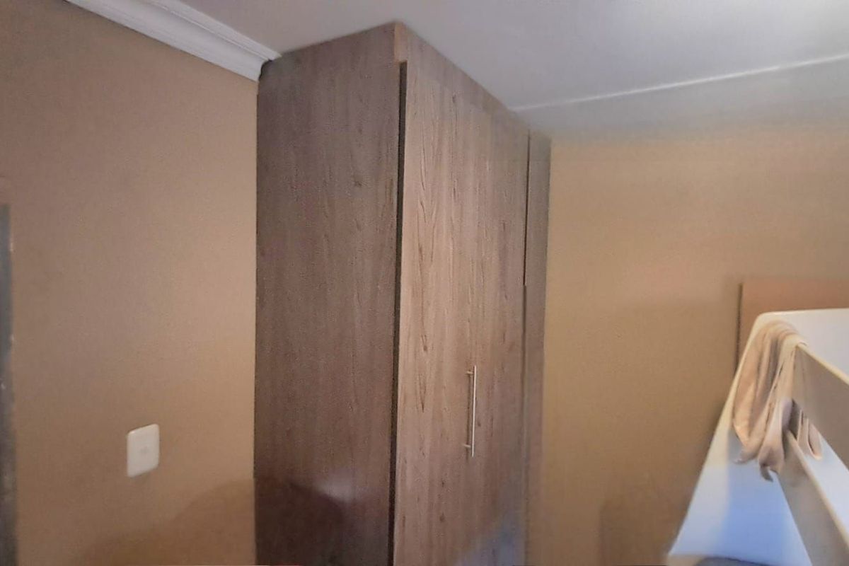 A bedroom featuring built-in wooden cabinetry with a modern finish and crown molding detail.