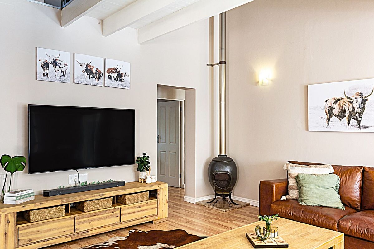 A cozy living room featuring a modern freestanding fireplace, exposed ceiling beams, and durable wood-look flooring.