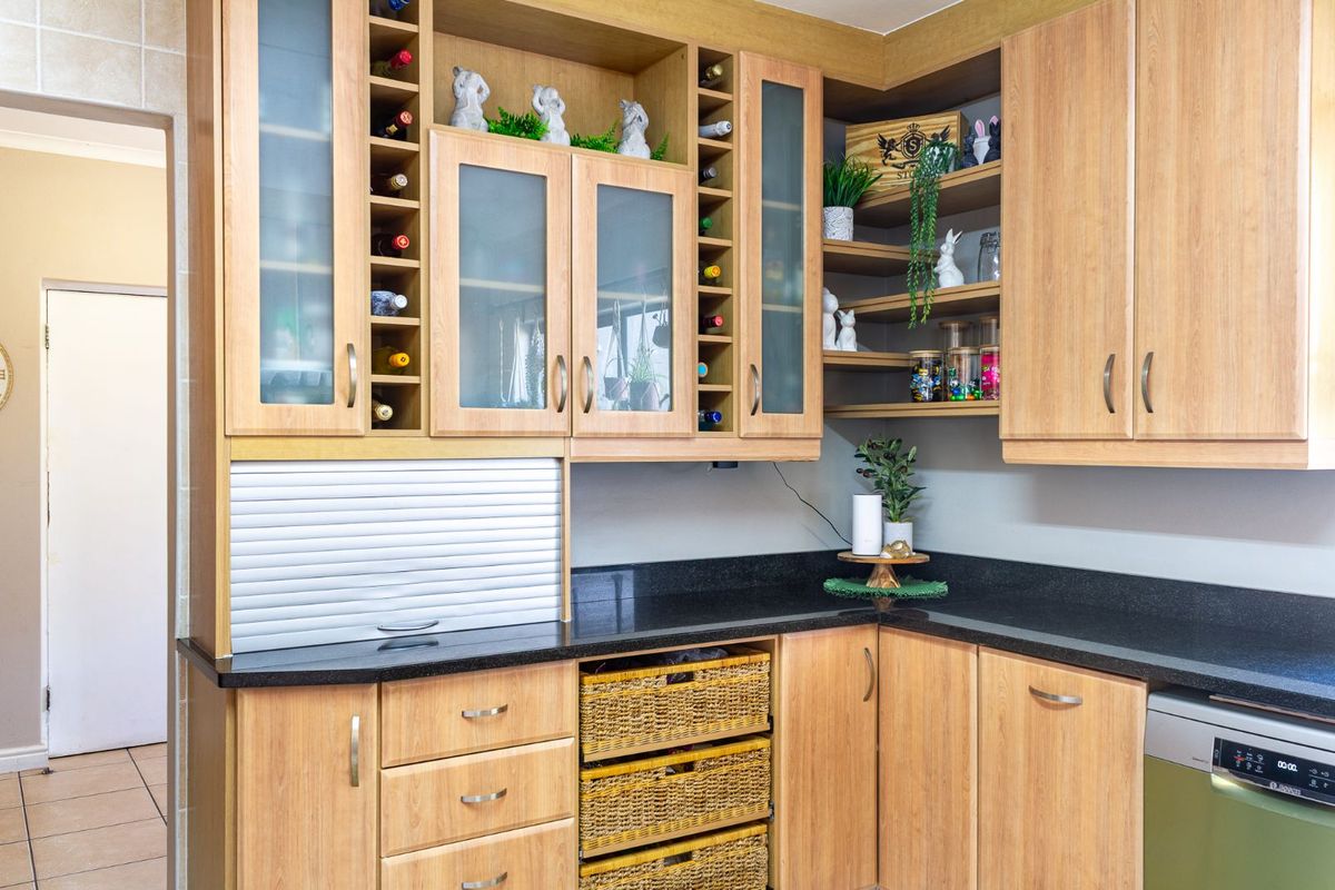 A functional kitchen corner featuring light wood cabinetry, black granite countertops, integrated wine storage, and a built-in dishwasher.