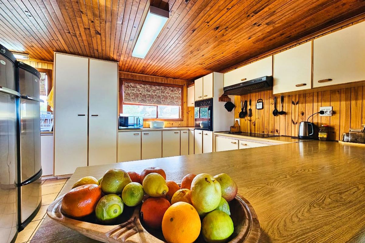 A functional kitchen featuring extensive timber paneling, laminate countertops, built-in oven, and ample cabinetry storage.