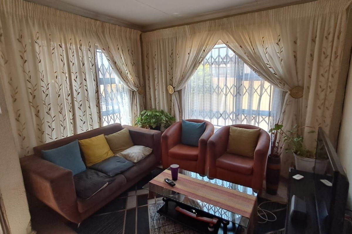 A cozy living room featuring large windows with security gates and fitted curtain tracks, providing natural light and a secure environment.