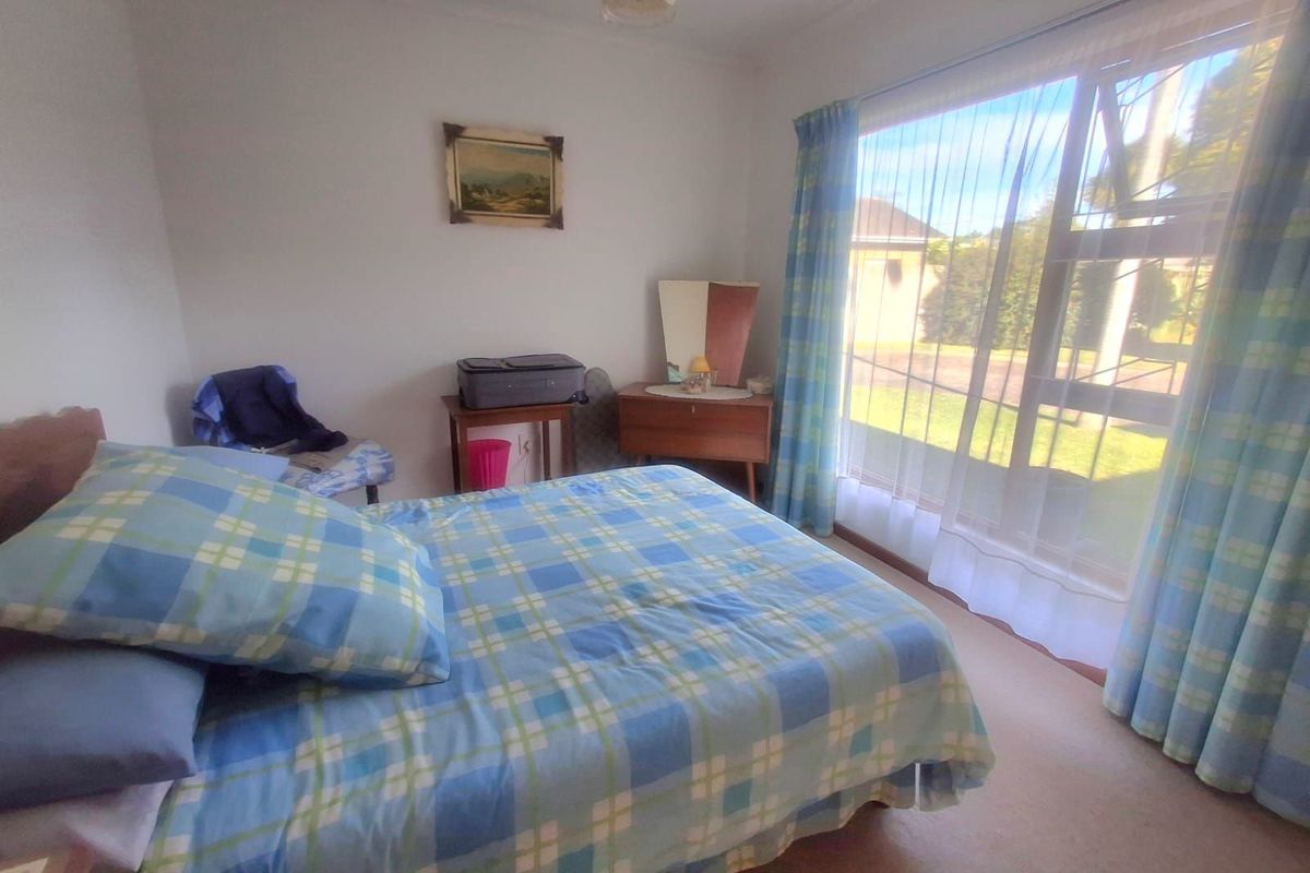 A bedroom featuring a large window with natural light, neutral walls, and carpeted flooring.