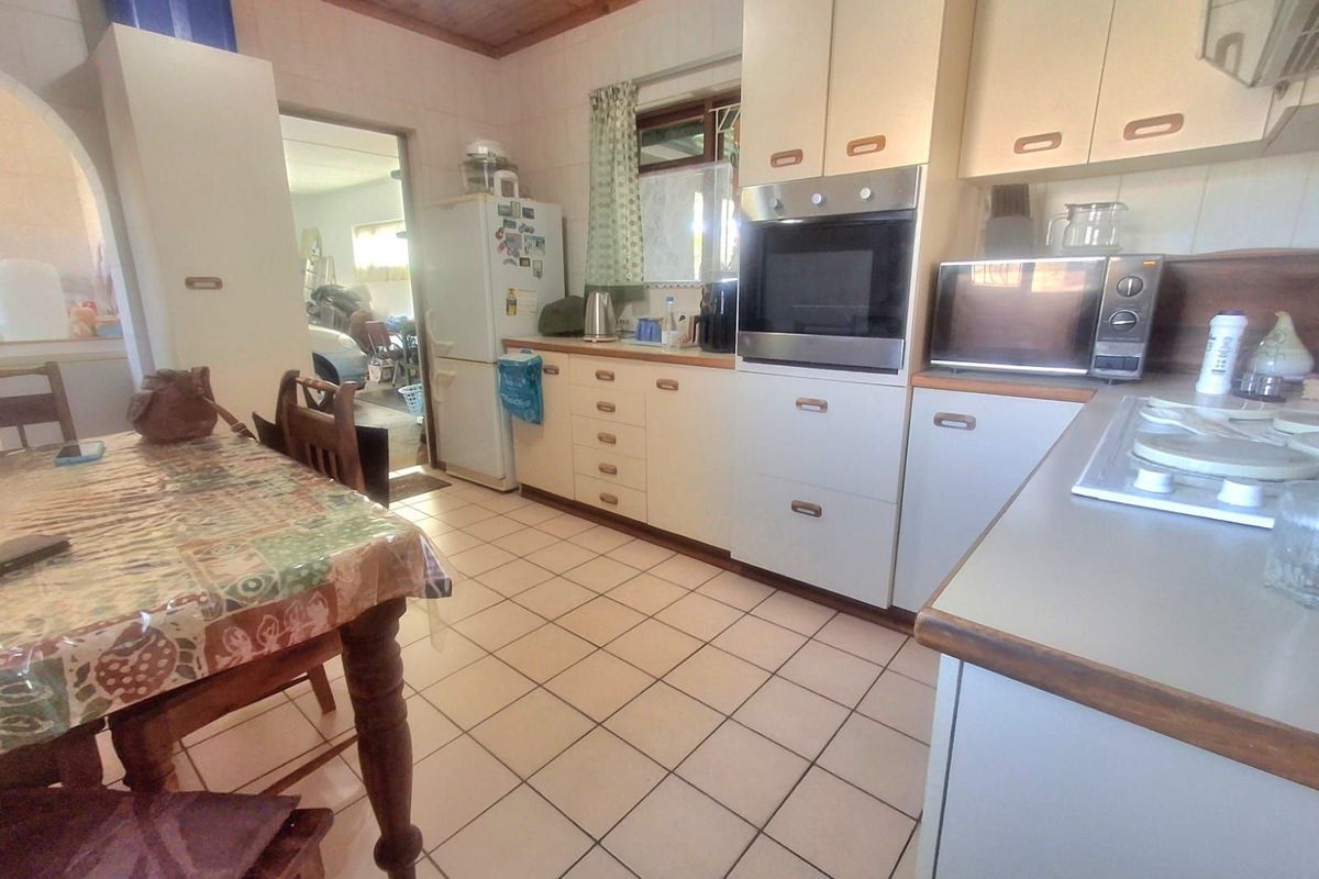 A functional kitchen featuring built-in cabinetry, integrated oven, and tiled flooring, offering a practical layout with direct access to adjacent living spaces.