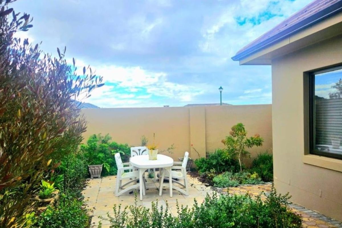 A private rear garden featuring a paved patio area, established perimeter wall, and landscaped garden beds adjacent to the main dwelling.