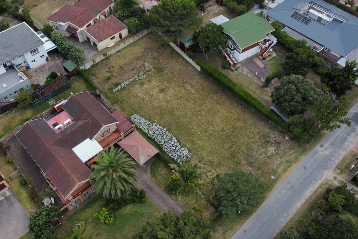 An aerial view of a vacant residential plot situated in a developed suburban neighborhood, featuring established boundary hedging and surrounding residential properties.