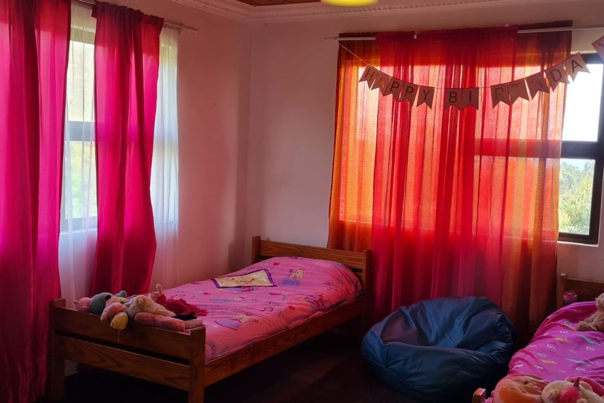 A bedroom featuring dual windows with natural light, wooden ceiling trim, and ample space for multiple beds.