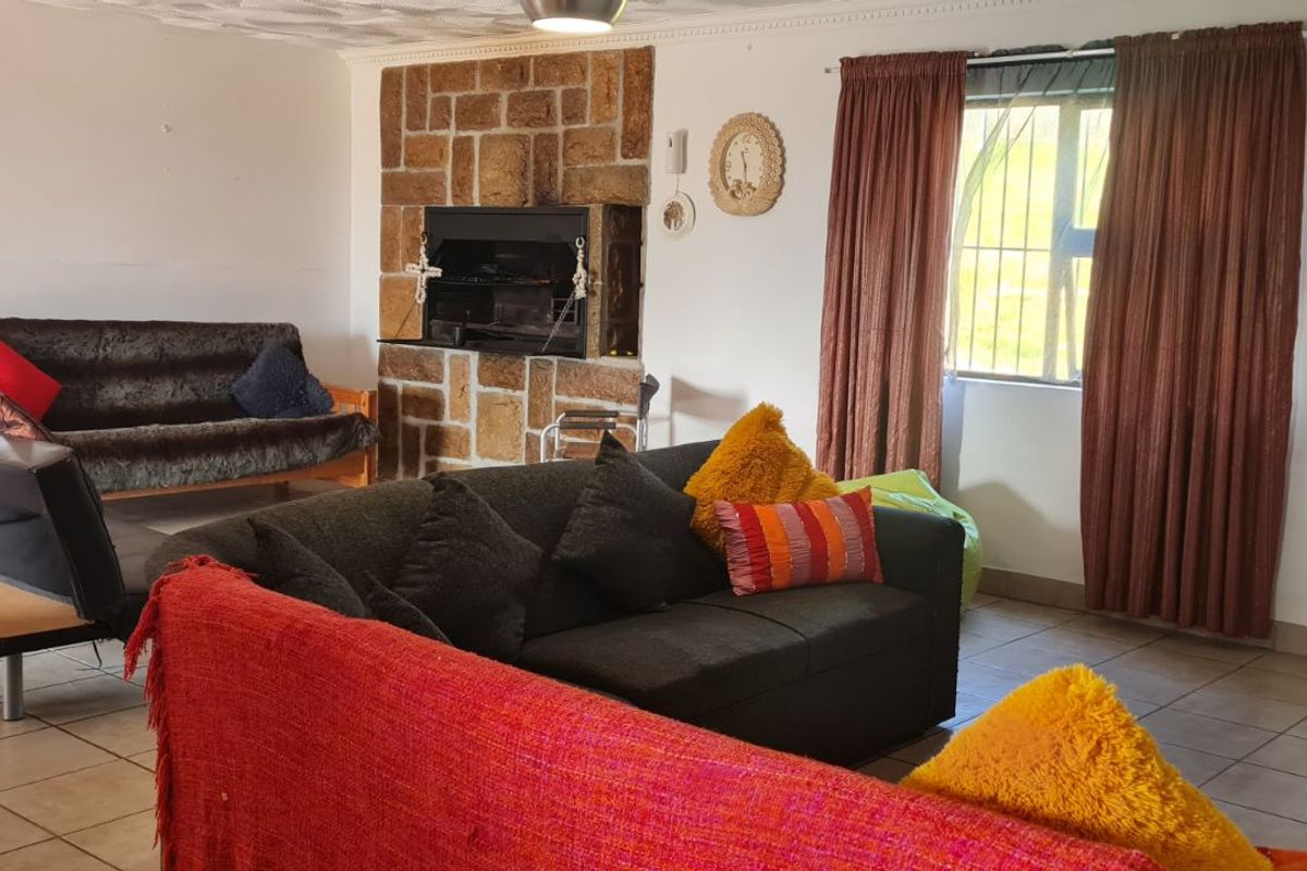 Spacious living room featuring a built-in stone fireplace, tiled flooring, and large windows with curtains, offering a comfortable and functional family living space.