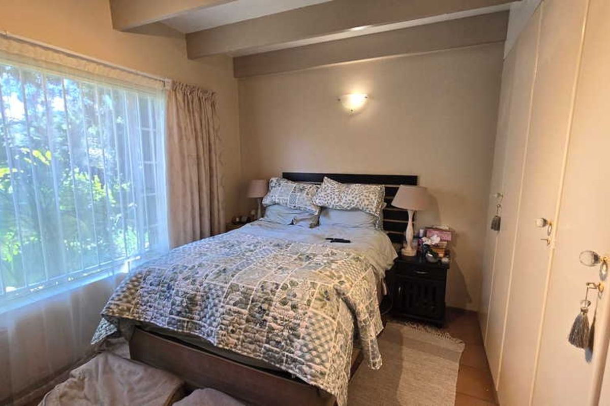 A cozy bedroom featuring built-in cupboards and exposed ceiling beams, providing a functional and comfortable living space.