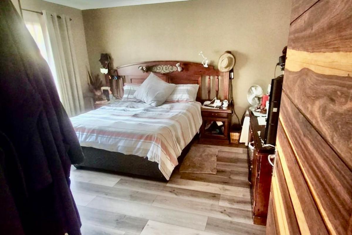 A bedroom featuring wood-look laminate flooring and a wood-paneled accent wall, providing a warm and functional living space.