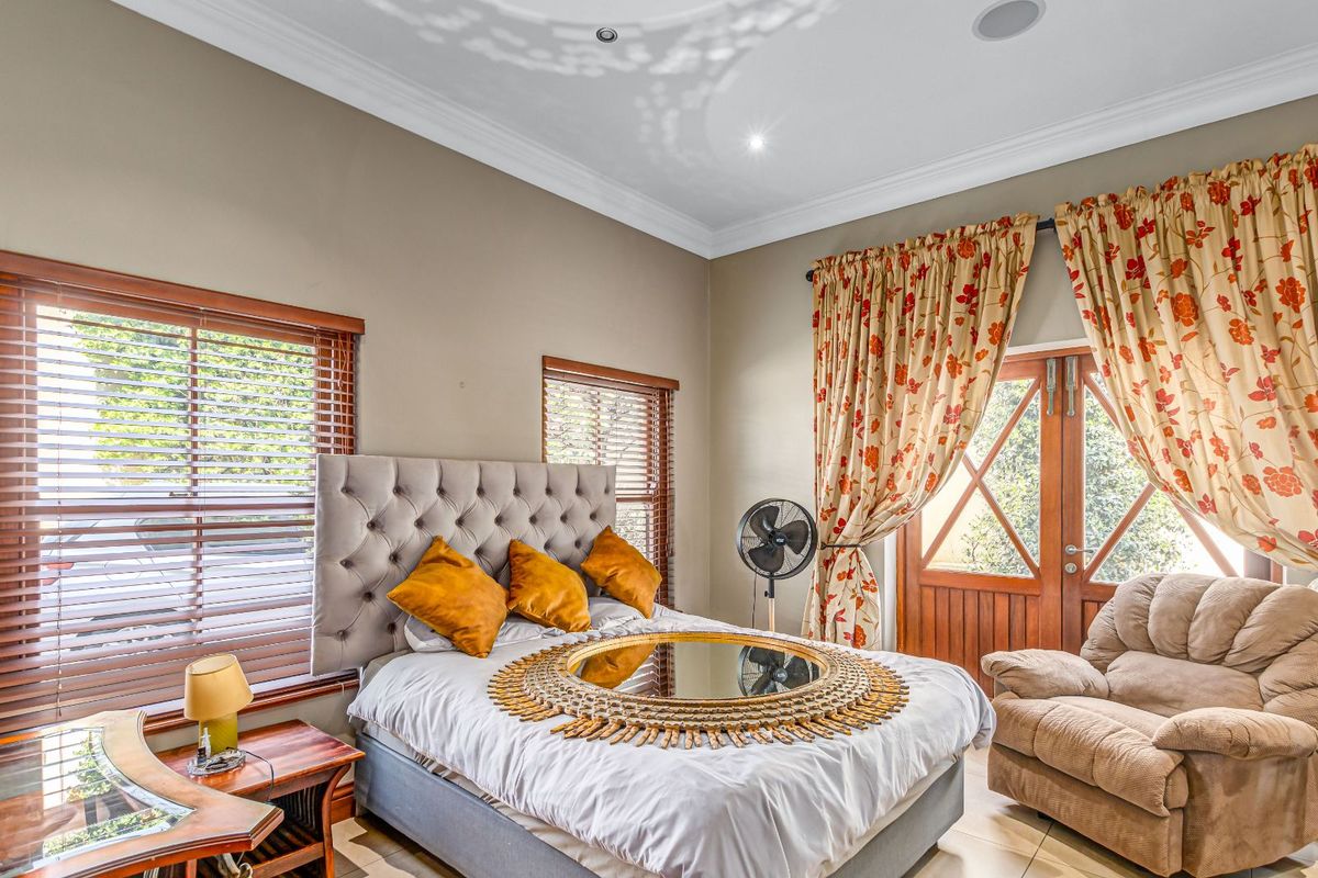 A well-lit bedroom featuring tiled flooring, crown molding, wooden window blinds, and double doors leading to an outdoor area.