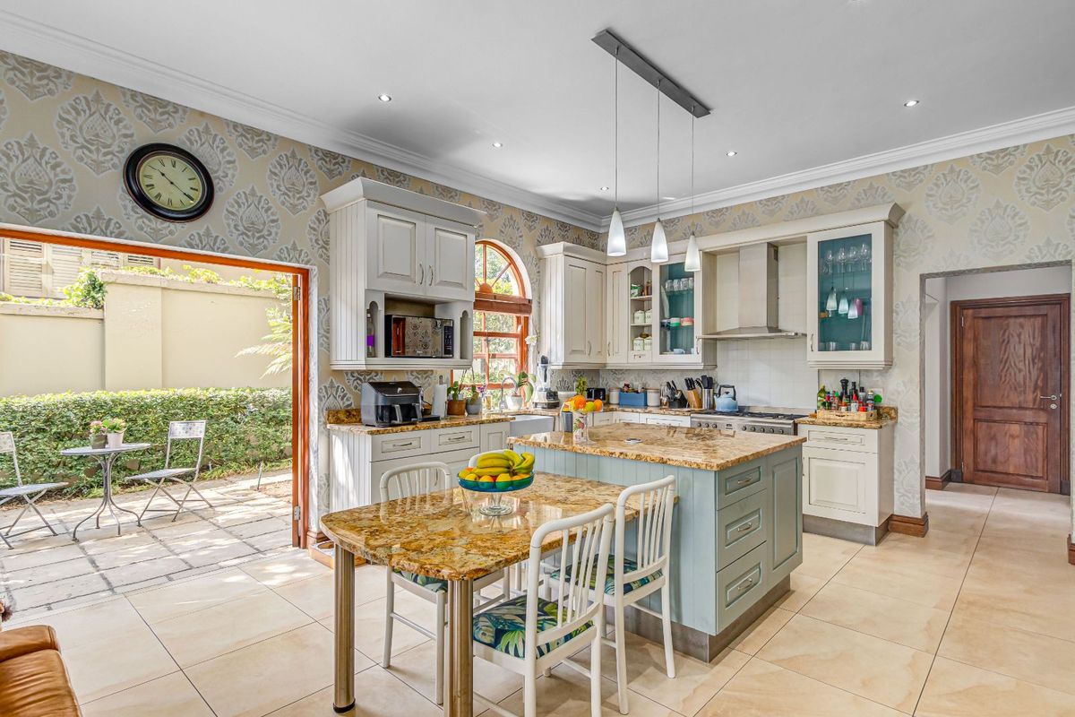 Spacious kitchen featuring a central island with granite countertops, custom cabinetry, integrated appliances, and direct access to an outdoor patio area.
