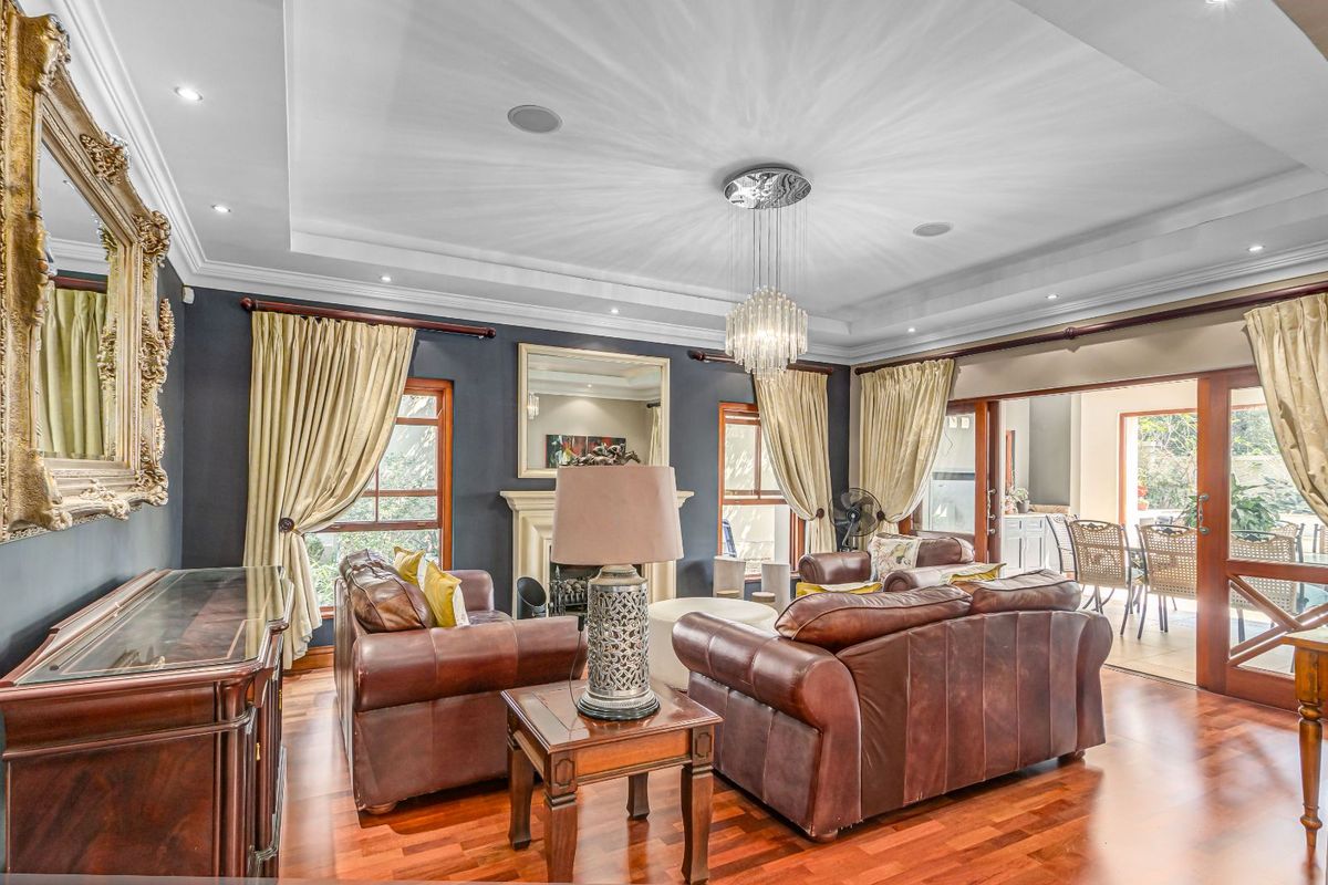 Spacious living room featuring a tray ceiling with recessed lighting, a central fireplace, and hardwood flooring, with seamless access to an adjoining patio area.
